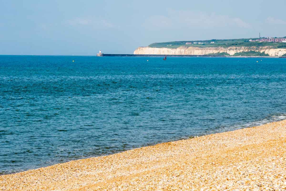 View from Newhaven beach across the water towards the chalk cliffs and harbour breakwater